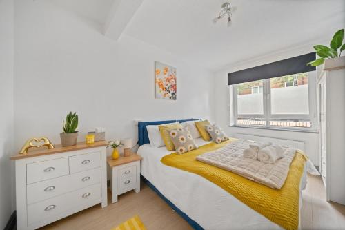 a bedroom with a bed with a yellow blanket and a window at Moro Luxe Homes in London