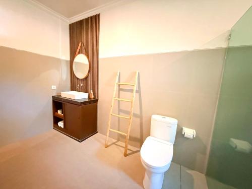 a bathroom with a toilet and a shelf and a mirror at Kelingking Tropical in batumadeg