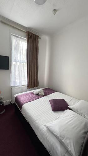 a bedroom with a large white bed with a window at Newham Hotel in London