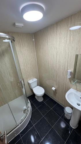 a bathroom with a shower and a toilet and a sink at Newham Hotel in London