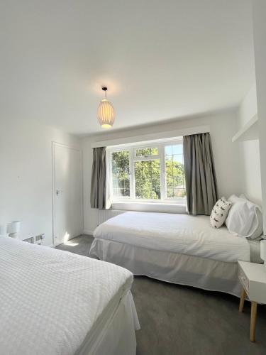 a white bedroom with two beds and a window at Lovely 2-Bedroom New Forest apartment on a Farm in New Milton