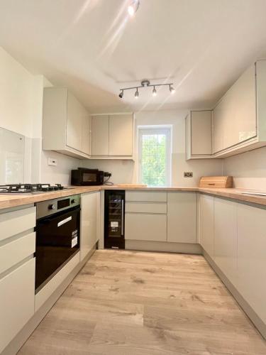 a kitchen with white cabinets and black appliances at Lovely 2-Bedroom New Forest apartment on a Farm in New Milton