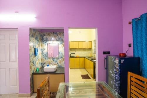 cocina con paredes de color púrpura y mesa de cristal en Peeliyatt riverview stays, en Kochi