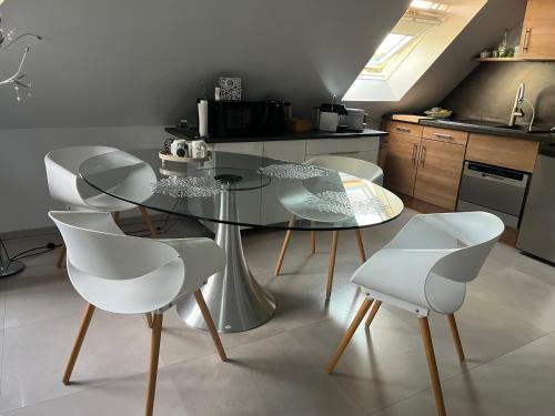 a kitchen with a glass table and white chairs at Studio Strasbourg in Niederhausbergen