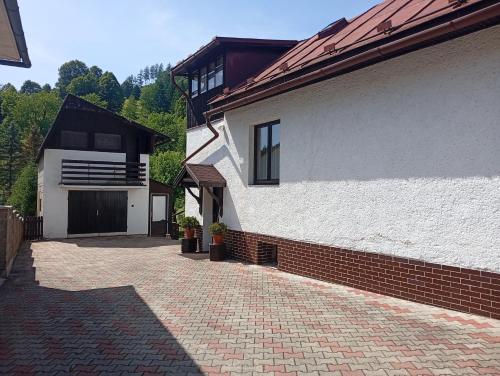 a house with a brick driveway next to a building at Rekreačný dom E&Z in Brezno