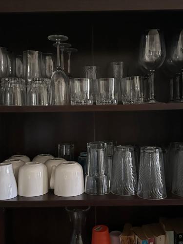 a shelf filled with glasses and other glass items at Spacious 3 Bed Home, Pool & Gym Access in Steer Town