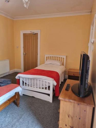 a bedroom with two beds and a tv on a table at Victoria Guest House in Bedford