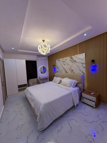 Un dormitorio con una gran cama blanca y una lámpara de araña. en Luxury 2BR 2BA Apartment in Lekki Ikota Ajah 247 Free Wifi and Family friendly, en Lekki
