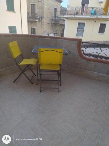 two yellow chairs and a table on a balcony at Mazzeo in Santa Maria di Castellabate