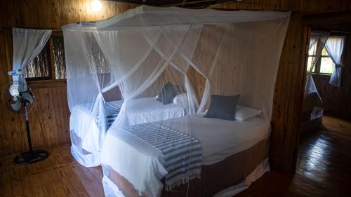 a bedroom with a canopy bed with white sheets and pillows at Viva O Sonho 