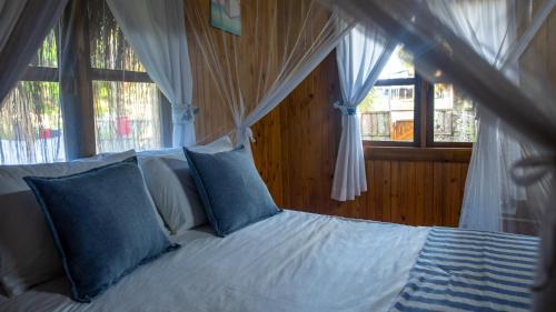a bed with blue pillows in a room with windows at Viva O Sonho 