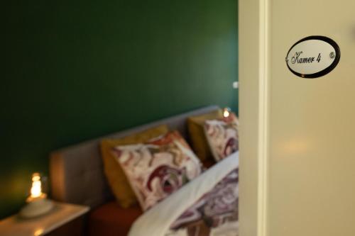a bedroom with a green wall and a bed with pillows at Klein Soestdijk in Veenhuizen