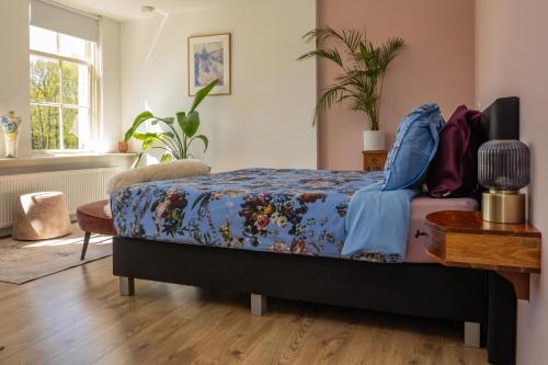 a bedroom with a bed with a blue comforter at Klein Soestdijk in Veenhuizen