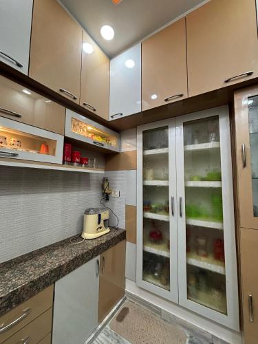 a kitchen with white cabinets with glass doors at DeeHa Niwas - A Banarasi Home in Varanasi