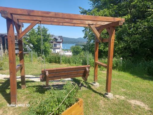 a wooden pergola with a bench in a field at Willa Domiwera in Polańczyk