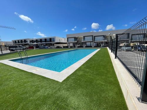 een zwembad met groen gras voor een gebouw bij Casa Familiar in Puerto Marino