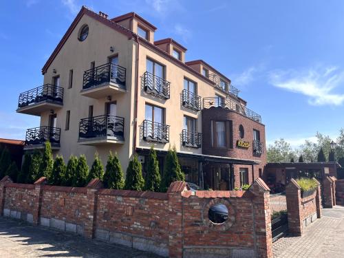 a large building with a brick fence in front of it at Gościniec Kaszebe in Łeba
