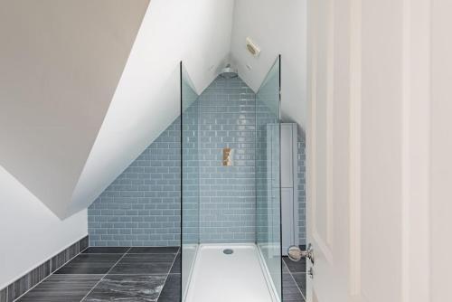 a bathroom with a shower with blue tiles at Holmwood by Keepers Cottages in Walmer