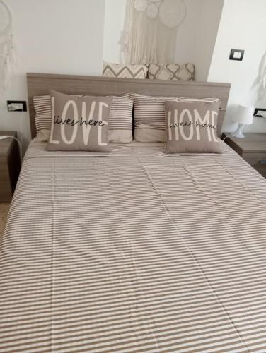 a bedroom with a large bed with striped sheets and pillows at HOME SWEET HOME Antonella in Valenzano