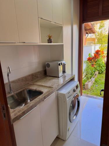 a kitchen with a sink and a washing machine at Casa espaçosa na Guarda do Embaú in Palhoça