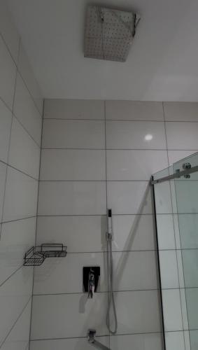 a shower in a bathroom with a white wall at Cozy, Serene Ambiance With Nice Balcony Views in Ikate