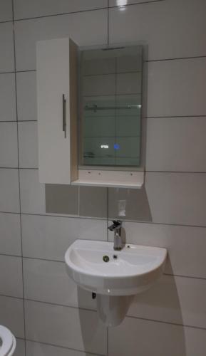 a white bathroom with a sink and a mirror at Cozy, Serene Ambiance With Nice Balcony Views in Ikate