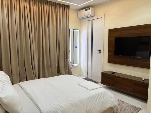 a bedroom with a bed and a flat screen tv at Cozy, Serene Ambiance With Nice Balcony Views in Ikate