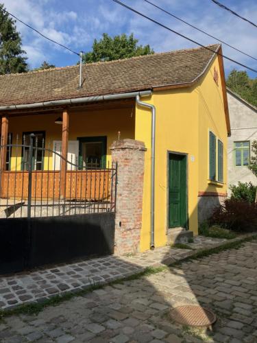 una casa gialla con una porta verde su una strada di Szent Flórián Tűzoltó Panzió Visegrád a Visegrád