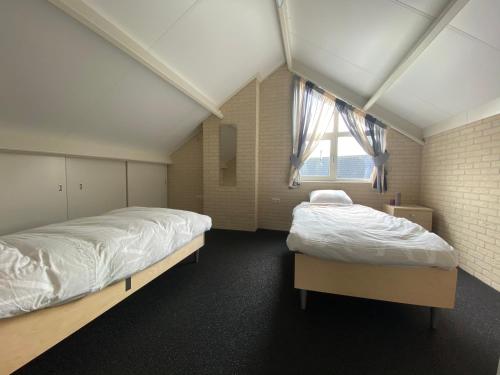 a bedroom with two beds and a window at Luxe vakantiewoning met stoomcabine en bubbelbad in Tzummarum