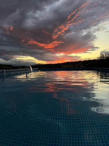 a swimming pool with a sunset in the water at B&B Itufi in Colonnella