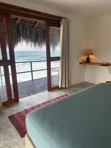 a bedroom with a bed and a view of the ocean at Finca Barlovento Cabaña, Tayrona in Los Naranjos