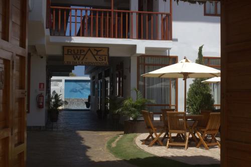 a patio with chairs and an umbrella on a street at Bungalows Rupay Wasi in Los Órganos