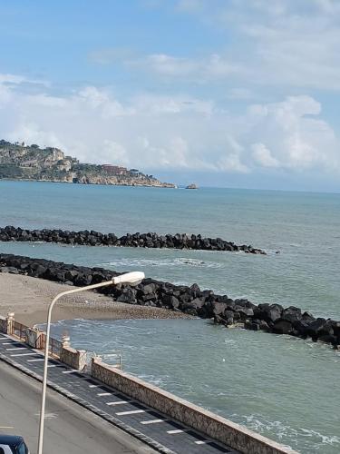 eine Straßenlaterne neben dem Meer mit Felsen im Wasser in der Unterkunft Maison Martina in Giardini-Naxos