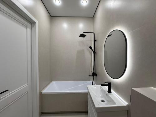 a bathroom with a tub and a sink and a mirror at Уютная квартира в ЖК Республика in Astana