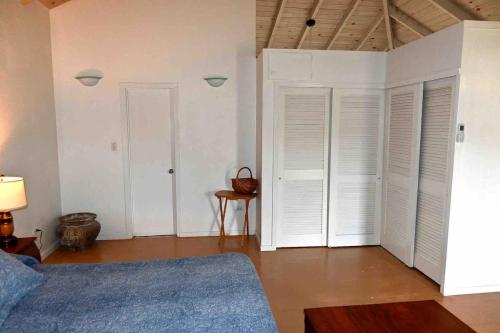 a bedroom with white walls and a bed with white shutters at Hummingbird Villa in Saint Johnʼs