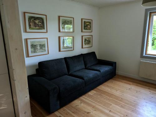 a black couch in a living room with pictures on the wall at Ferienhaus in Borghamn, Vättern in Borghamn