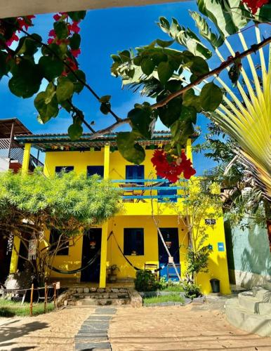 a yellow house with a palm tree in front of it at Capitólio 01 hospedagem Rua nascer do sol 03 Canoa Quebrada in Aracati
