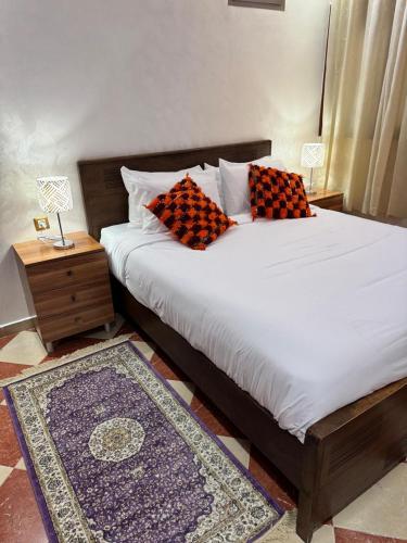 ein Bett mit zwei Kissen darauf mit einem Nachttisch in der Unterkunft Top7dBASMALA 1 in Salé