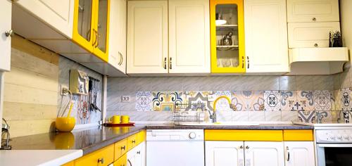 a kitchen with white cabinets and yellow counters at ZNK Family House in Skopje