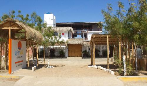 a building with a sign and trees in front of it at Bungalows Rupay Wasi in Los Órganos