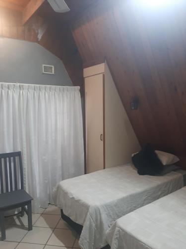 a bedroom with two beds and a window and a chair at AD'S Overnight Accommodation in Richards Bay