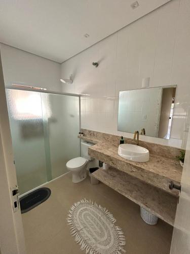 a bathroom with a sink and a toilet and a mirror at A Casa Azul in Peruíbe
