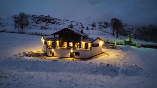 a house lit up with lights in the snow at Edelweiss Mountain Lodge in Brda