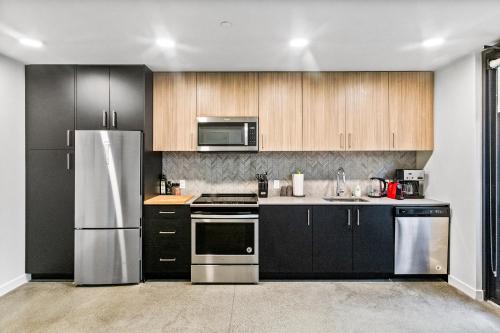 a kitchen with stainless steel appliances and wooden cabinets at Open Loft in Redmond Core - 92 Walkscore! in Redmond