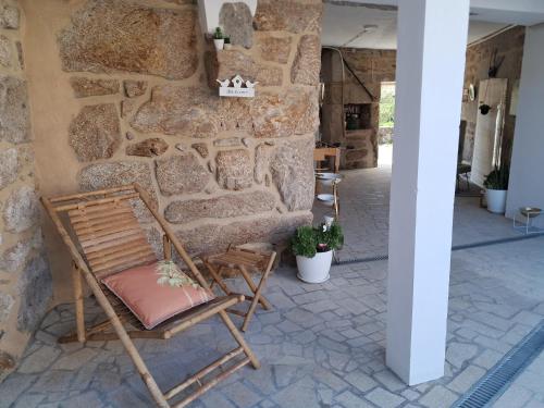 a wooden chair sitting next to a stone wall at Ninho das Andorinhas in Monção