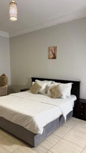 a bedroom with a large bed with white sheets and pillows at شقق النورس in Rayyis