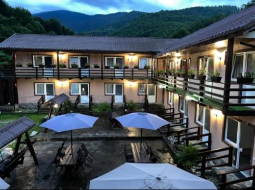 a hotel with tables and umbrellas in front of a building at Pensiunea Flora in Cîrţişoara