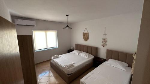 a bedroom with two beds and a window at Boho Apartment Himara in Himare