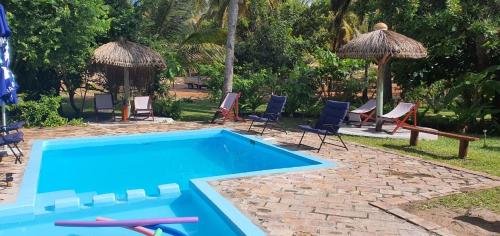 a blue swimming pool with chairs and umbrellas at Viva O Sonho 