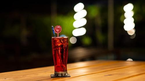 a red drink with a toothpick in it on a table at Viva O Sonho 